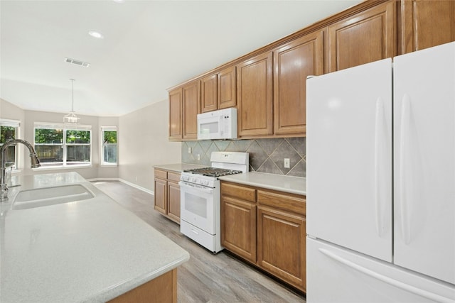 kitchen with white appliances, a sink, light wood finished floors, light countertops, and decorative backsplash