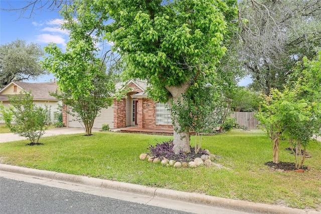 view of property hidden behind natural elements with a garage, driveway, and brick siding