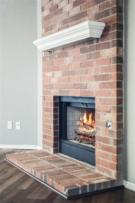 detailed view of baseboards, a fireplace, and wood finished floors