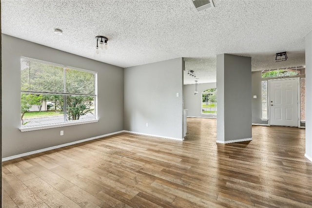 empty room featuring wood finished floors, baseboards, and a textured ceiling