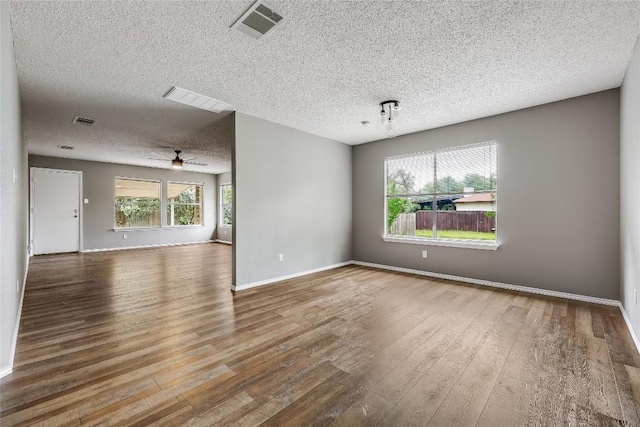 spare room featuring a textured ceiling, wood finished floors, a ceiling fan, and baseboards