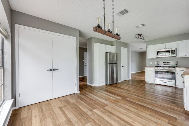 3109 Blazing Star Trl, Cedar Park, TX 78613 - kitchen with stainless steel appliances, light wood-style flooring, light countertops, white cabinetry, and a textured ceiling
