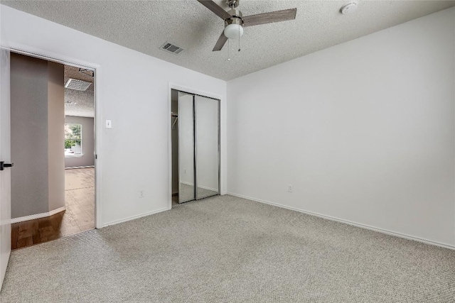 unfurnished bedroom with a textured ceiling, carpet floors, a closet, and ceiling fan