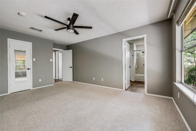 unfurnished bedroom with carpet floors, a textured ceiling, baseboards, connected bathroom, and ceiling fan
