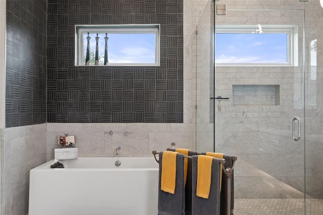 full bathroom with a bath, plenty of natural light, a shower stall, and tile walls
