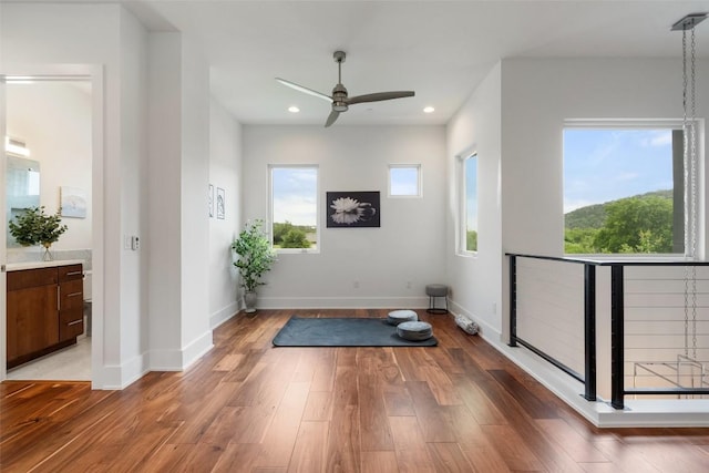 workout area featuring a ceiling fan, healthy amount of natural light, light wood-type flooring, recessed lighting, and baseboards