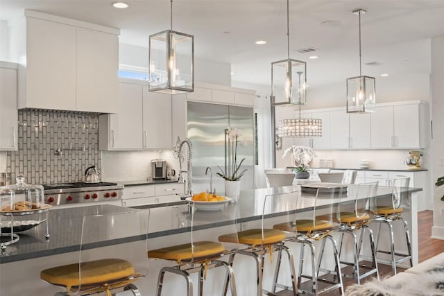 908 Cypress Grove Dr, Austin, TX 78732 - kitchen with dark countertops, a kitchen breakfast bar, stainless steel built in fridge, tasteful backsplash, and recessed lighting