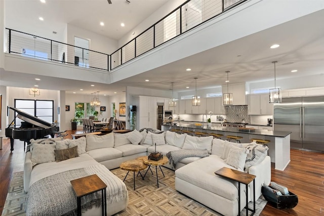 living area with a high ceiling, light wood-style floors, a chandelier, and recessed lighting