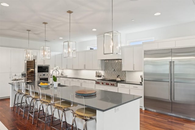kitchen featuring appliances with stainless steel finishes, dark countertops, dark wood-style floors, decorative backsplash, and white cabinetry