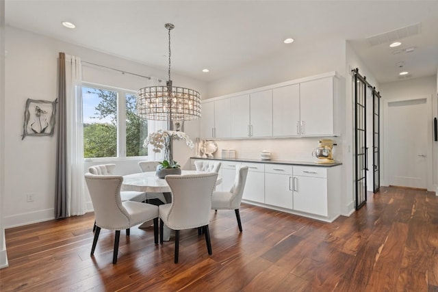 dining area with a barn door, dark wood-type flooring, baseboards, a chandelier, and recessed lighting