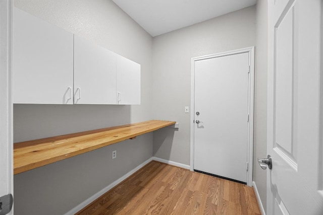 258 Whispering Wind Dr, Georgetown, TX 78633 - laundry room with light wood-type flooring, a desk, and baseboards