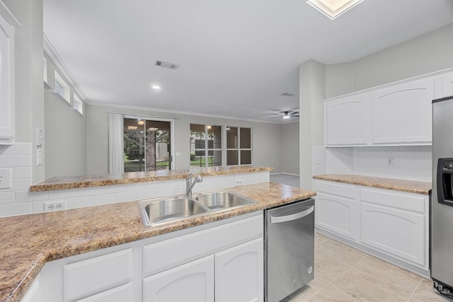 258 Whispering Wind Dr, Georgetown, TX 78633 - kitchen featuring appliances with stainless steel finishes, a sink, decorative backsplash, white cabinetry, and plenty of natural light