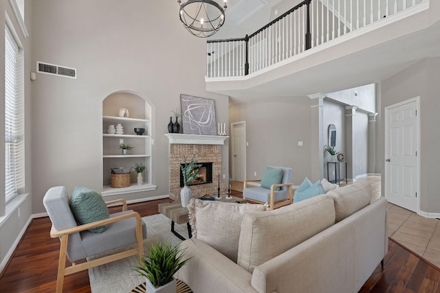 9013 Lantana Way, Austin, TX 78749 - living room featuring a towering ceiling, a brick fireplace, baseboards, wood finished floors, and built in shelves