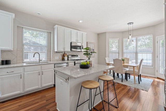9013 Lantana Way, Austin, TX 78749 - kitchen with appliances with stainless steel finishes, a sink, white cabinets, dark wood finished floors, and backsplash