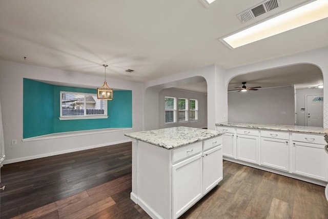 7516 Marble Crest Dr, Austin, TX 78747 - kitchen with arched walkways, white cabinetry, dark wood-type flooring, ceiling fan, and light stone counters