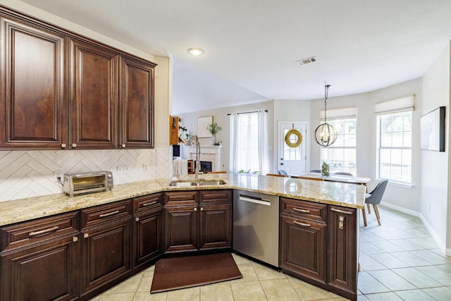 2113 Spring Hollow Path, Round Rock, TX 78681 - kitchen featuring dishwasher, a peninsula, decorative backsplash, light tile patterned flooring, and a fireplace
