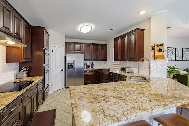 2113 Spring Hollow Path, Round Rock, TX 78681 - kitchen with appliances with stainless steel finishes, a sink, a peninsula, under cabinet range hood, and light stone countertops
