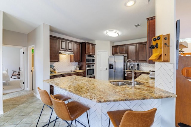 2113 Spring Hollow Path, Round Rock, TX 78681 - kitchen featuring appliances with stainless steel finishes, a peninsula, under cabinet range hood, and backsplash