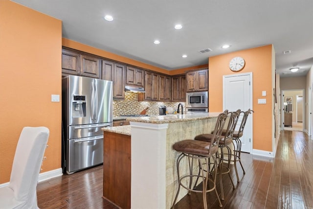 4332 Teravista Club Dr Unit 69, Round Rock, TX 78665 - kitchen featuring stainless steel appliances, dark wood finished floors, under cabinet range hood, baseboards, and tasteful backsplash