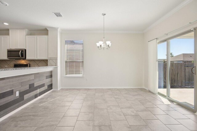 212 Mauldin St, Georgetown, TX 78628 - kitchen with stainless steel microwave, white cabinets, crown molding, a chandelier, and light countertops