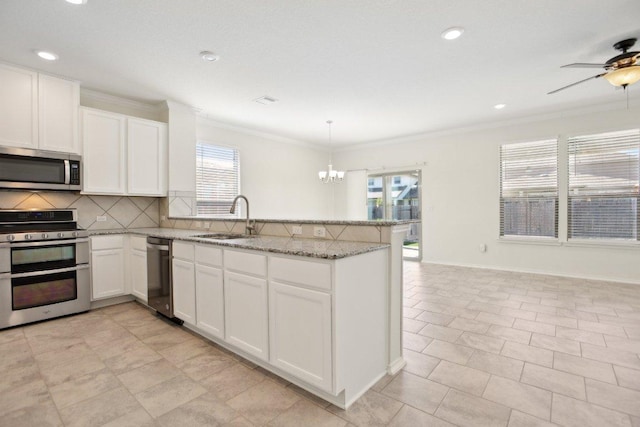 212 Mauldin St, Georgetown, TX 78628 - kitchen featuring appliances with stainless steel finishes, a sink, a peninsula, crown molding, and decorative backsplash