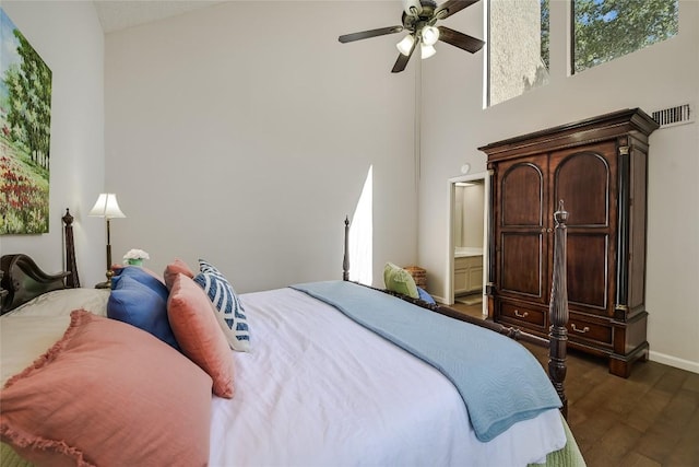 bedroom with dark wood-type flooring, a high ceiling, baseboards, a ceiling fan, and connected bathroom
