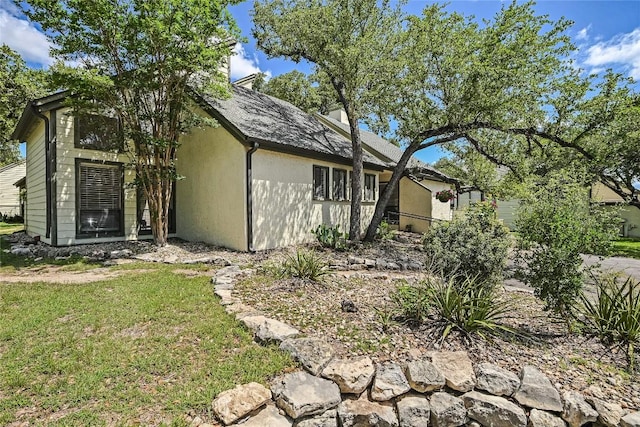view of property exterior with stucco siding and a yard