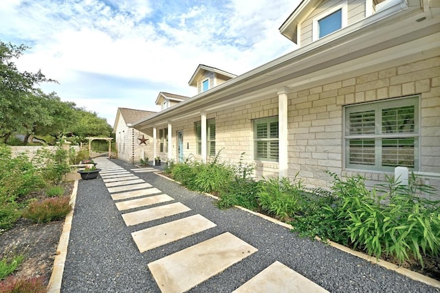 view of property exterior featuring stone siding and a porch