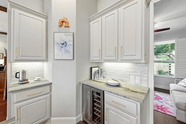 indoor bar with wine cooler, decorative backsplash, baseboards, ceiling fan, and crown molding
