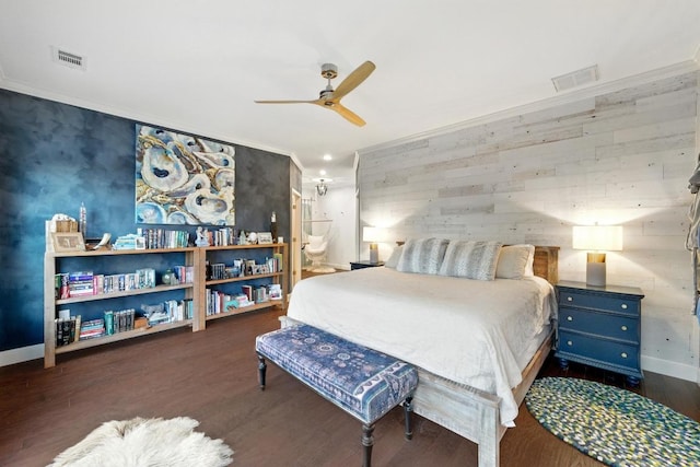 bedroom with wood finished floors, baseboards, ornamental molding, ensuite bath, and ceiling fan
