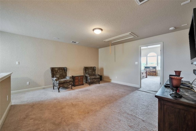 living area with attic access, carpet flooring, a textured ceiling, and baseboards