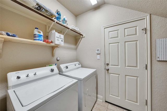 laundry room with washer and clothes dryer, light tile patterned floors, and a textured wall