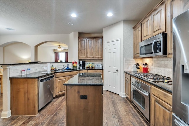 kitchen featuring appliances with stainless steel finishes, a kitchen island, dark wood-style floors, recessed lighting, and a textured ceiling