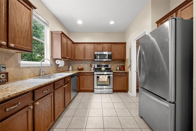 5228 Bantom Woods Bnd, Austin, TX 78724 - kitchen featuring stainless steel appliances, a sink, decorative backsplash, light tile patterned floors, and brown cabinets