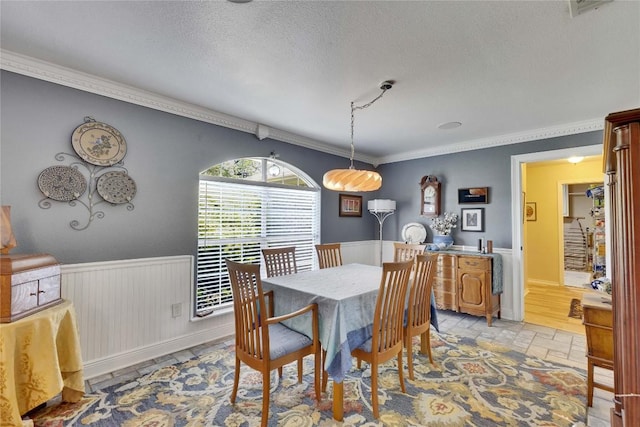 240 2 Mile Ln, Smithville, TX 78957 - dining space with a textured ceiling, crown molding, a wainscoted wall, and light stone finish flooring