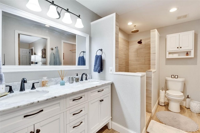 240 2 Mile Ln, Smithville, TX 78957 - bathroom with wood finished floors, tiled shower, double vanity, toilet, and recessed lighting
