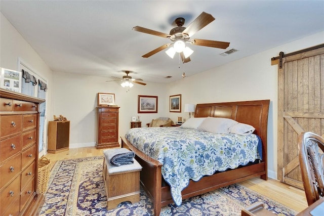 240 2 Mile Ln, Smithville, TX 78957 - bedroom featuring light wood finished floors, a barn door, ceiling fan, and baseboards