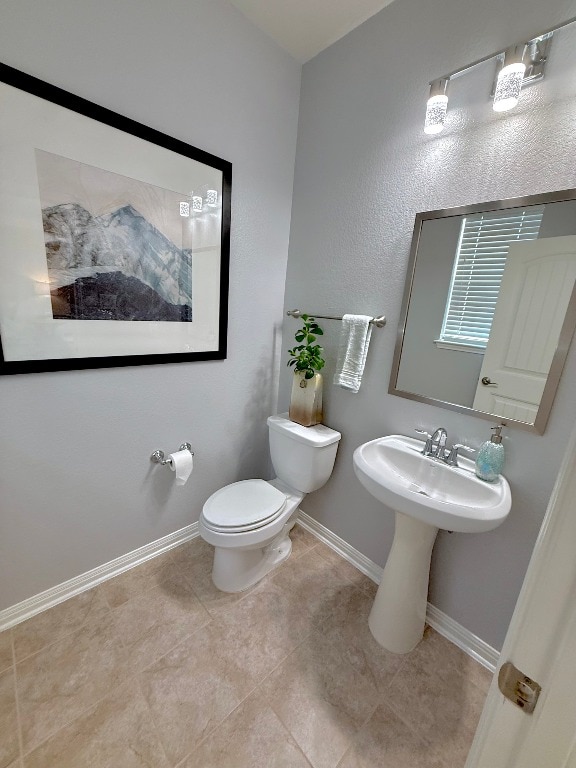 bathroom featuring toilet, baseboards, and tile patterned floors