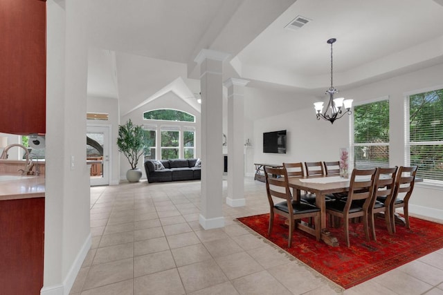 dining space featuring baseboards, light tile patterned flooring, ornate columns, a chandelier, and a raised ceiling