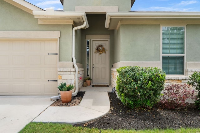 doorway to property featuring an attached garage, stucco siding, and stone siding
