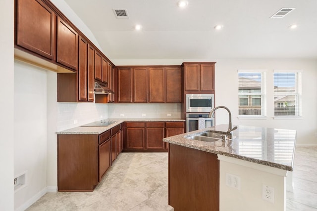 kitchen with a sink, stainless steel appliances, light stone countertops, tasteful backsplash, and recessed lighting