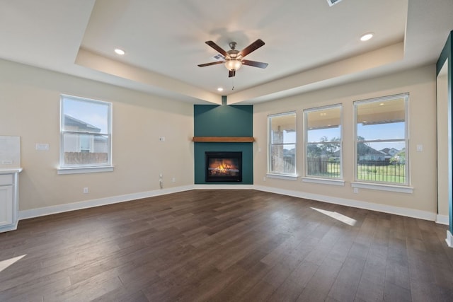 159 Nodena Dr, Dripping Springs, TX 78620 - unfurnished living room featuring a tray ceiling, a ceiling fan, a glass covered fireplace, healthy amount of natural light, and recessed lighting
