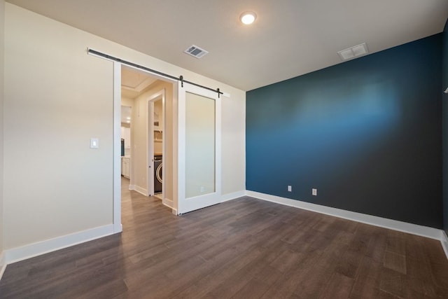 159 Nodena Dr, Dripping Springs, TX 78620 - unfurnished room featuring a barn door, dark wood-style flooring, washer / dryer, and baseboards