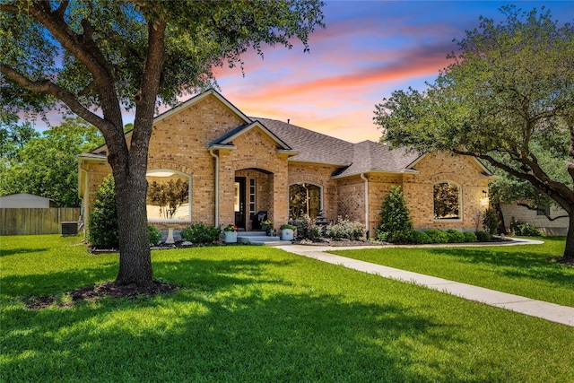view of front of home featuring brick siding, central air condition unit, and a shingled roof