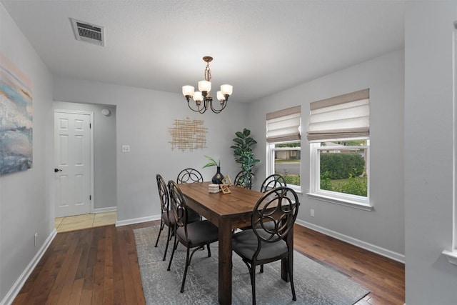 dining space with a chandelier, hardwood / wood-style floors, and baseboards