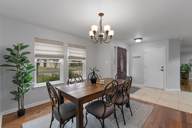 dining room featuring a chandelier, light wood-style flooring, and baseboards