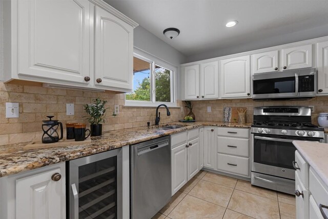 kitchen featuring stainless steel appliances, wine cooler, a sink, and white cabinets