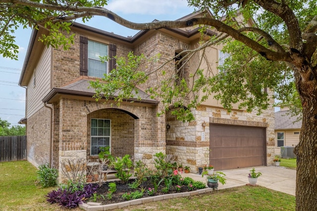 view of front of home with a garage, cooling unit, driveway, fence, and brick siding
