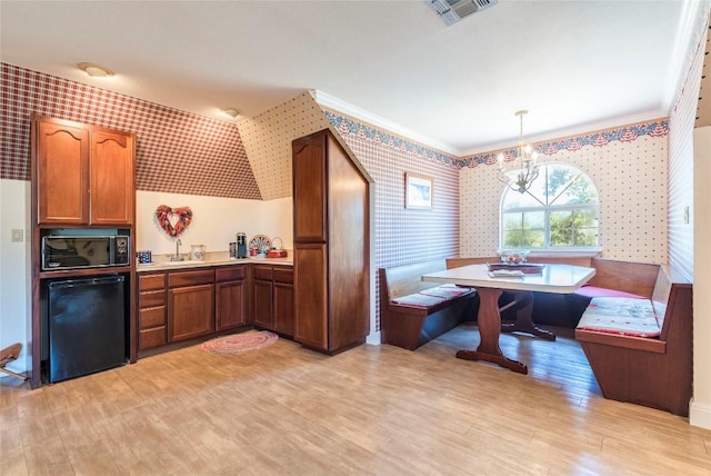 17270 Fm 112, Thrall, TX 76578 - kitchen with wallpapered walls, black dishwasher, breakfast area, a chandelier, and light wood-style floors