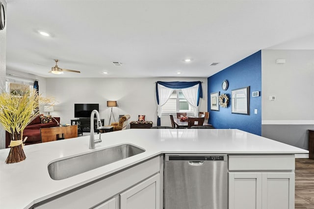 kitchen with stainless steel dishwasher, open floor plan, a sink, wood finished floors, and light countertops